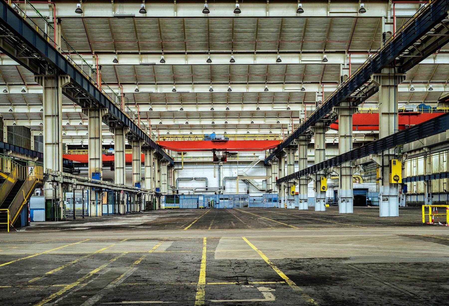 large empty warehouse with steel pillars and pipes along the wall